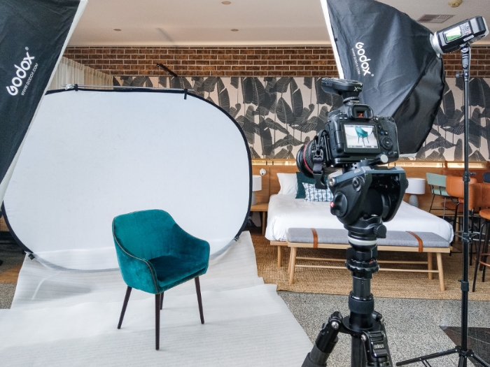 Behind the scenes of a Melbourne product photography furniture shoot. Professional camera on a tripod photographing a blue chair with flashes.