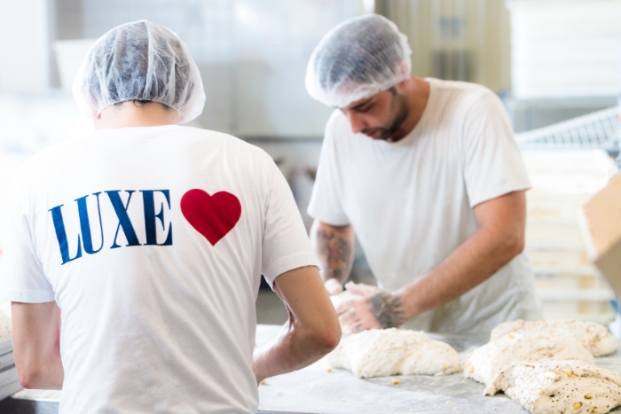 Commercial advertising photo showing two bakers in Sydney's CDB shaping bread. The shirts have their brand on them.