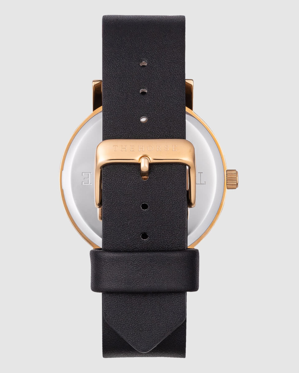 image of a gold watch with black strap back view