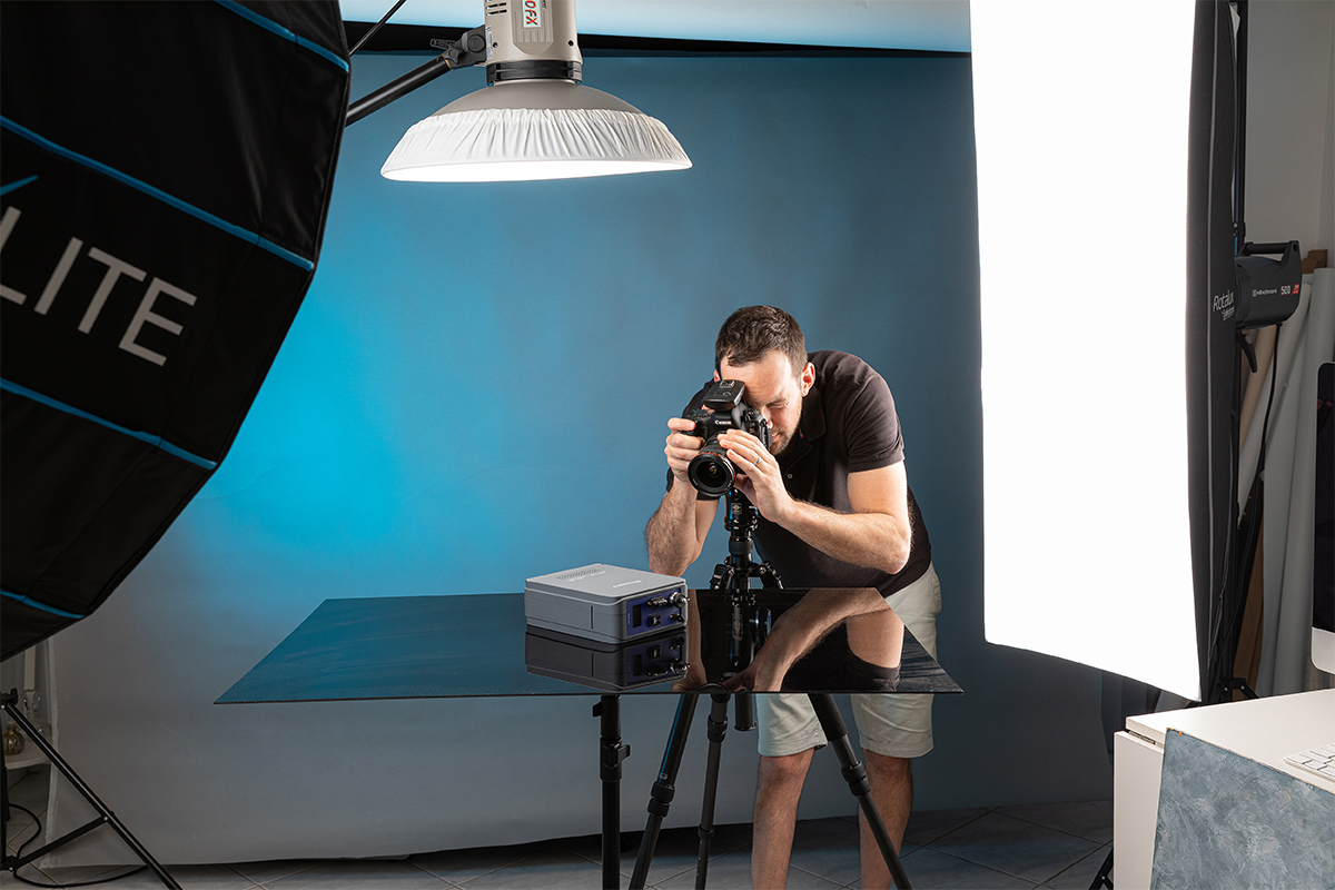 Shows Amazon product photographer Adrian Harrison in a Sydney photography studio taking a photograph of a product on a black background. Studio lights can be seen.