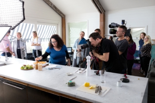 Food stylist in Sydney styling food for a food photographer. Video crew in background and creative agency staff onlooking.