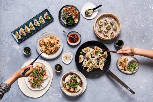 Social media food photography image of many Asian dumpling dishes being shared. 