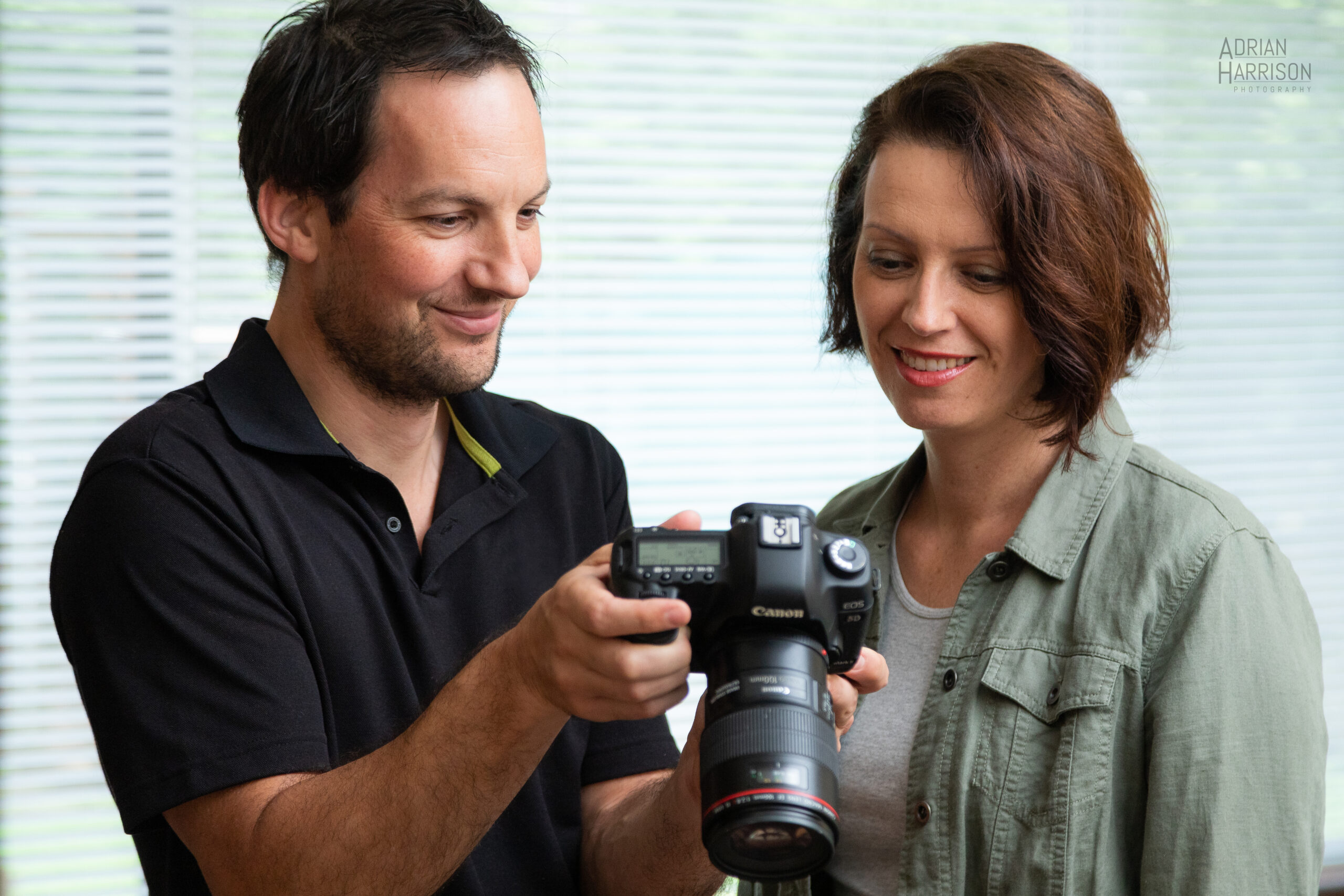 Corporate photography expert Adrian Harrison with Sydney based client showing photos of a photoshoot on a camera.